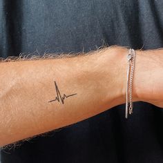 a man's arm with a heartbeat tattoo on it