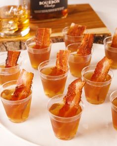 small cups filled with different types of food on a white plate next to a bottle