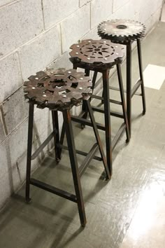 three metal stools sitting against a brick wall