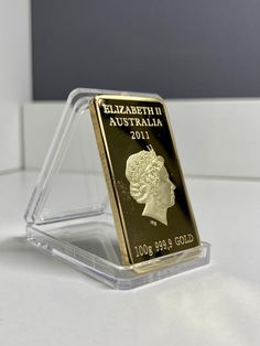 an australian gold coin is displayed in a clear holder on a white countertop with a black background