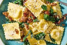 a blue plate topped with ravioli and spinach covered in cheese, meat and seasoning