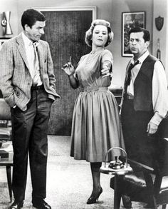 an old black and white photo of two men and a woman standing in a living room