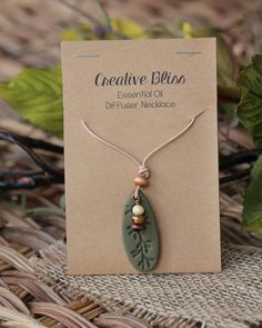 a necklace with a leaf and bead on it sitting on top of a card