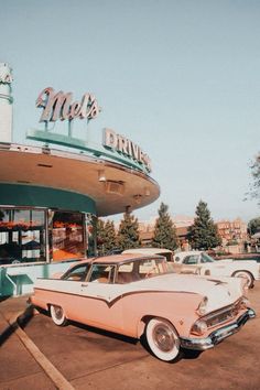 an old pink car parked in front of a diner