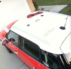 a red and white car with hello kitty decals on the roof is parked in front of a garage