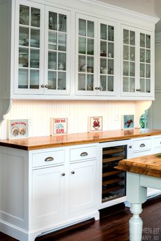 a kitchen with white cabinets and wooden counter tops on a hard wood flooring area