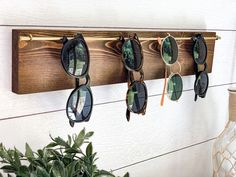 sunglasses are hanging on a wooden rack in front of a potted plant