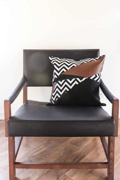 a black leather chair with two pillows on it and a brown pillow sitting on the back