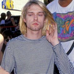 a man with blonde hair talking on a cell phone while standing next to another man