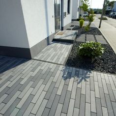 the sidewalk is lined with small plants and graveled walkways on both sides of the building