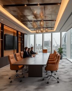 two people sitting at a conference table in front of large windows looking out on the city