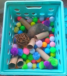 a blue basket filled with lots of different colored balls and pom - poms