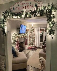 a living room decorated for christmas with lights on the fireplace and a dog sitting in the doorway