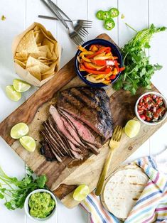 sliced steak on a cutting board with chips, salsa and lime wedges next to it