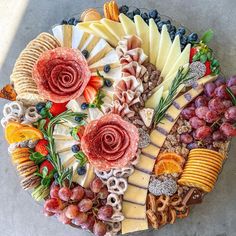 an assortment of cheeses, fruits and meats arranged in a circular arrangement on a platter