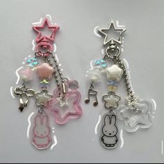 two key chains with charms attached to them on a white surface, one is pink and the other is blue