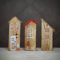 three small wooden houses with red roof and windows on them, one is made out of wood