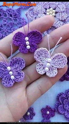 three crocheted butterflies are being held in someone's hand with pearls on them