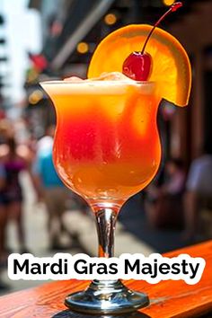 a colorful drink sitting on top of a wooden table next to a building with the words mardi gras majestic