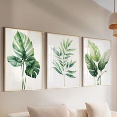 three green leaves are hanging on the wall above a white couch in a living room