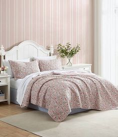 a white bed sitting in a bedroom next to a window with pink flowers on it