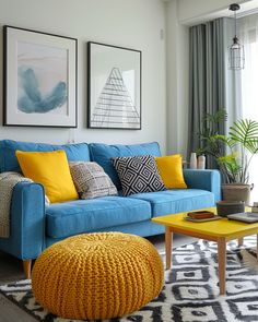 a living room with blue couches and yellow ottomans on the floor, two framed pictures above them