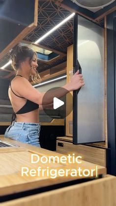 a woman is standing in front of a refrigerator and pointing at the door with her right hand