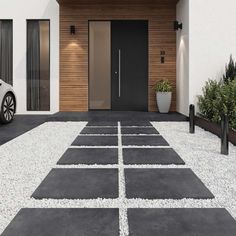 a car is parked in front of a modern house with black and white gravel on the driveway