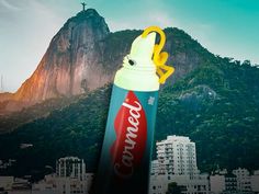 a can of coca - cola on top of a mountain with buildings in the background