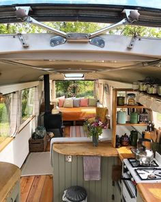 the inside of a camper with wood flooring and kitchen counter tops, stove top oven