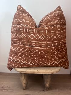 a brown and white pillow sitting on top of a wooden bench