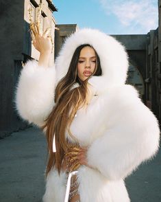 a woman in a white fur coat posing for the camera