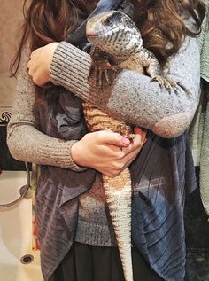 a woman holding a small lizard in her arms