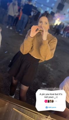 a woman is taking a selfie with her cell phone while wearing a sweater and skirt