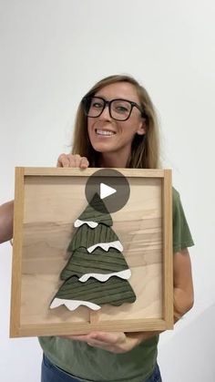 a woman holding up a wooden cutout of a christmas tree