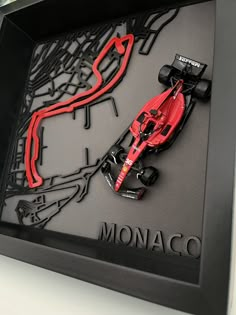 a red race car is on display in a black shadow box with the word monaco