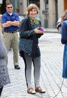 a woman standing on the street holding a purple object