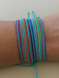 a person's arm with several different colored bracelets on top of each other