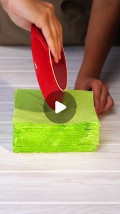 a person using a red paddle on top of a green cloth to clean the floor