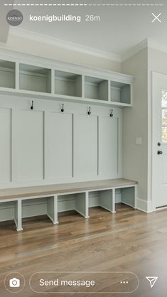 an empty room with several white benches and some cabinets on the wall, in front of a door