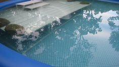 an empty swimming pool with trees reflected in the water