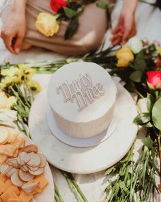 a white cake sitting on top of a table next to flowers and other food items