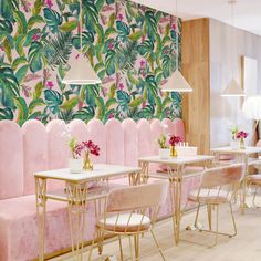 a restaurant with pink velvet booths and tropical wallpaper