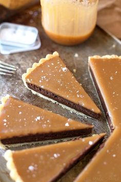 a chocolate tart pie with slices cut out on a table next to a jar of orange juice