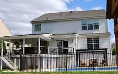 a large white house with a pool in the yard and a black fence around it