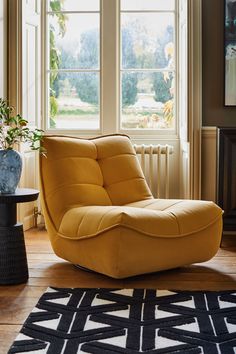 a yellow chair sitting on top of a hard wood floor next to a black table