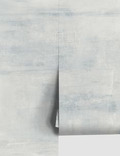 an abstract painting with white and grey colors on the wall, including one corner missing