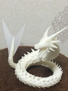 a white dragon figurine sitting on top of a brown pillow next to a wall