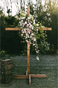 a cross with flowers on it in the grass