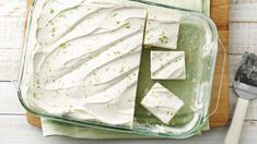 a glass dish filled with white frosting next to a spatula